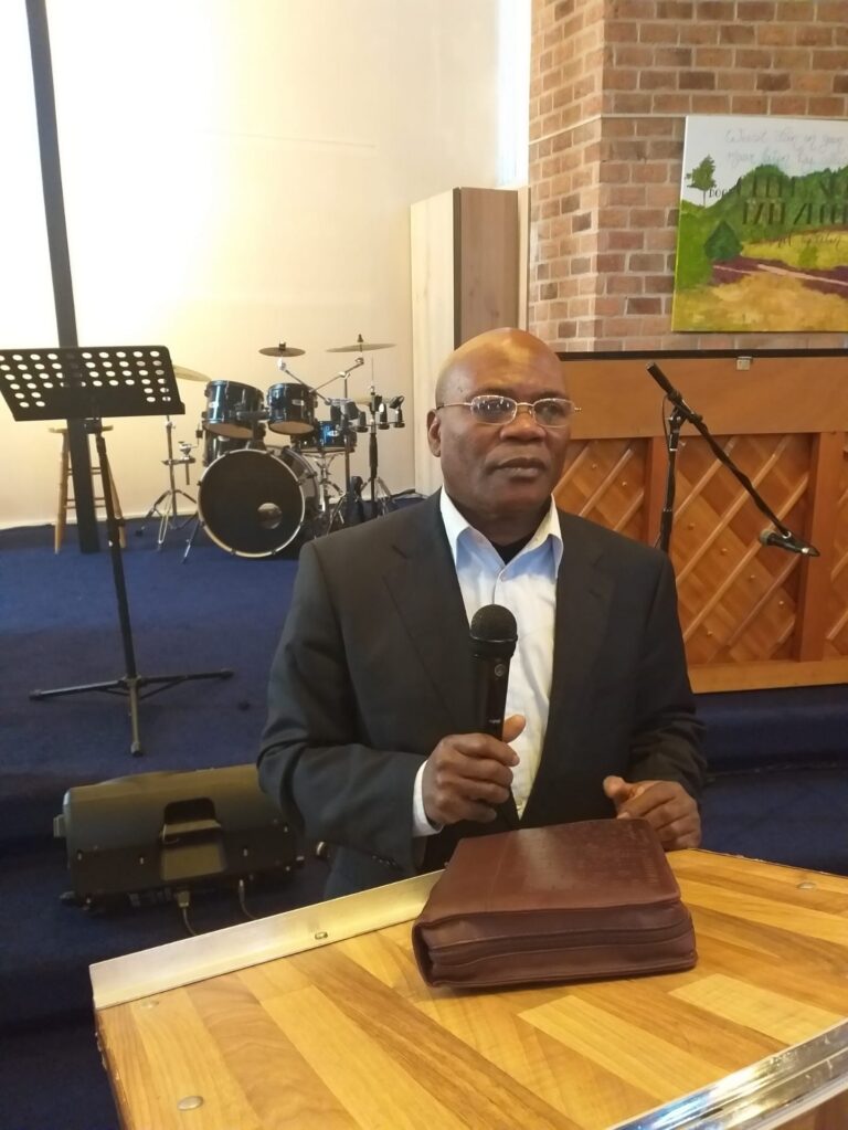 Voorganger Inacio Gomes da Silva achter de lessenaar tijdens een dienst, met microfoon en bijbel